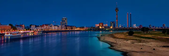 Der Rhein in Düsseldorf mit dem Rheinturm am Abend, von der Oberkasseler Brücke aus gesehen